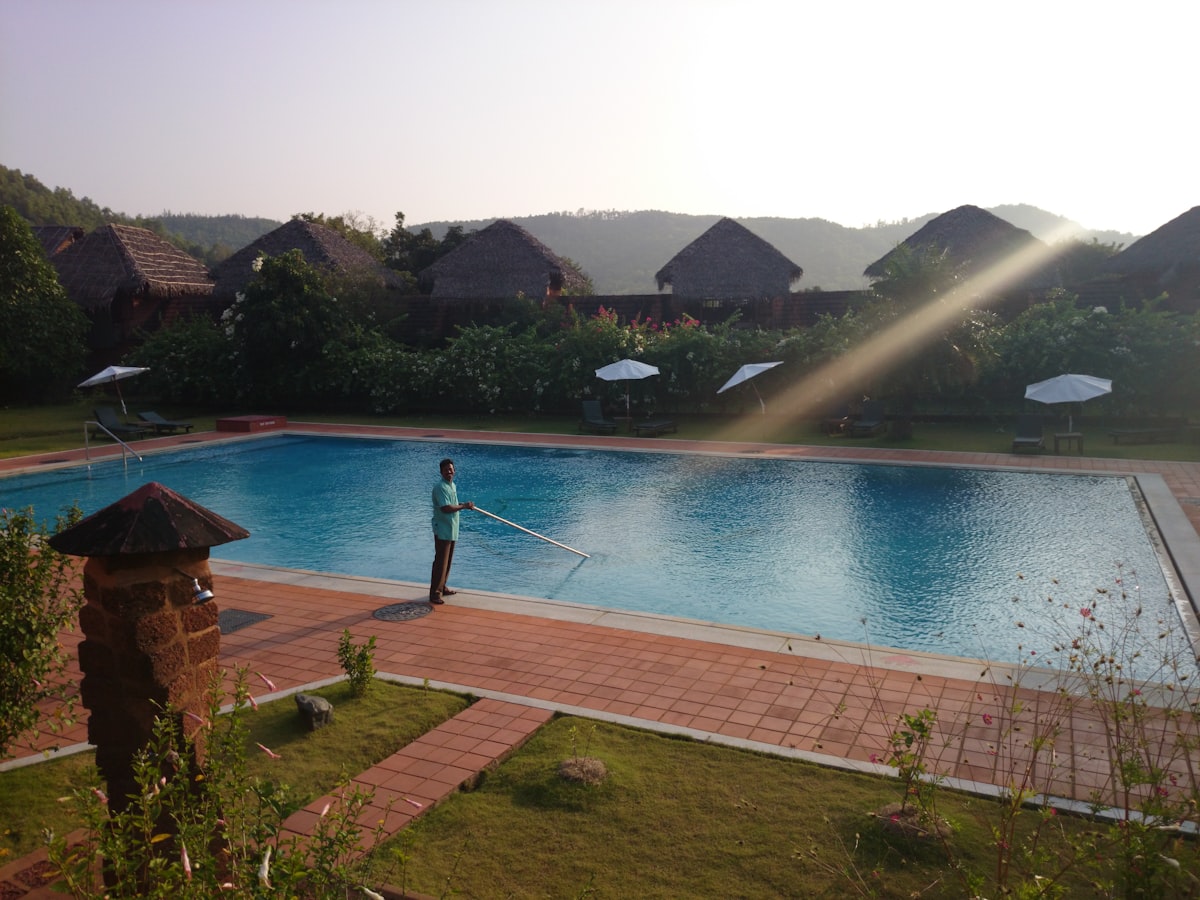 Pool technician cleaning a backyard swimming pool