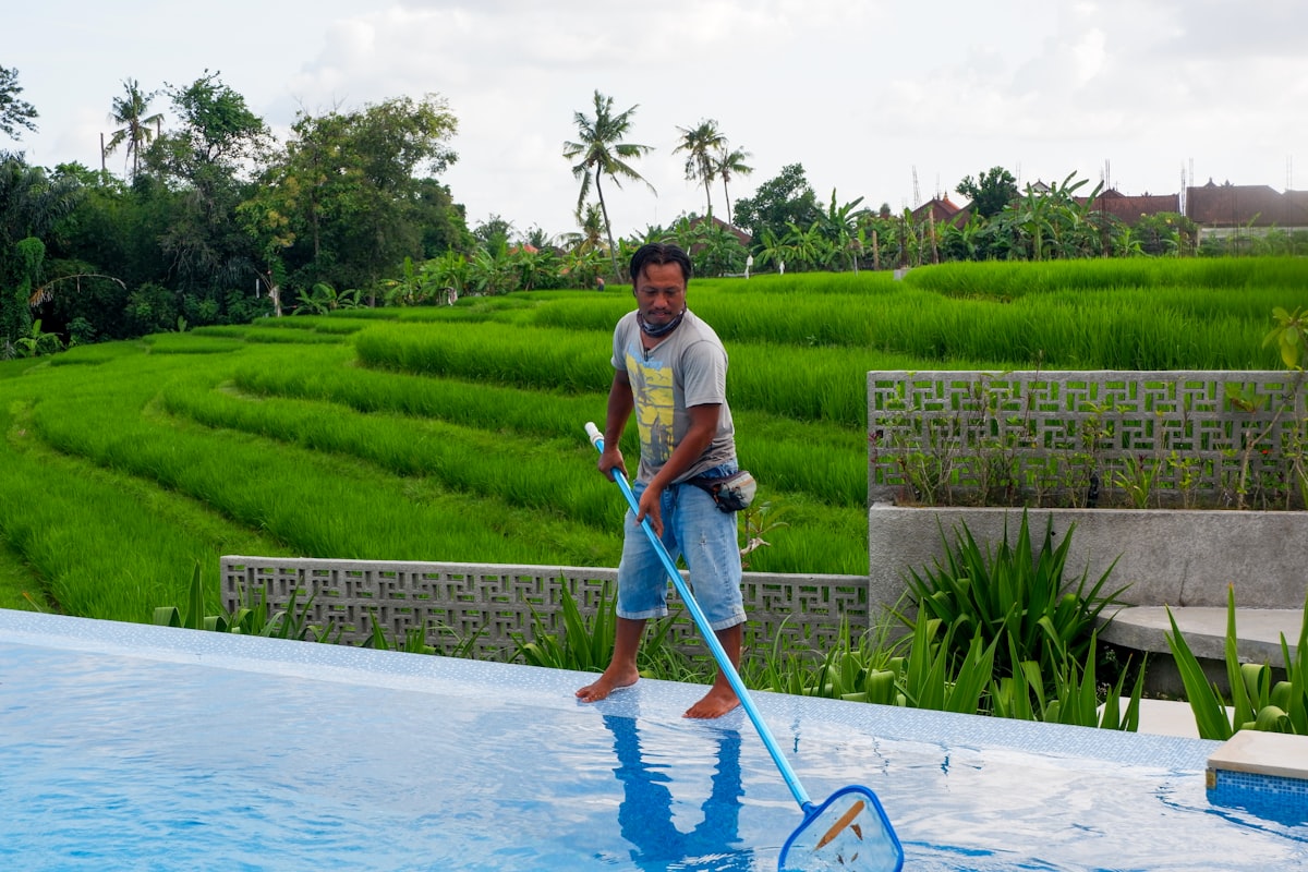 Pool service professional walking beside a backyard pool